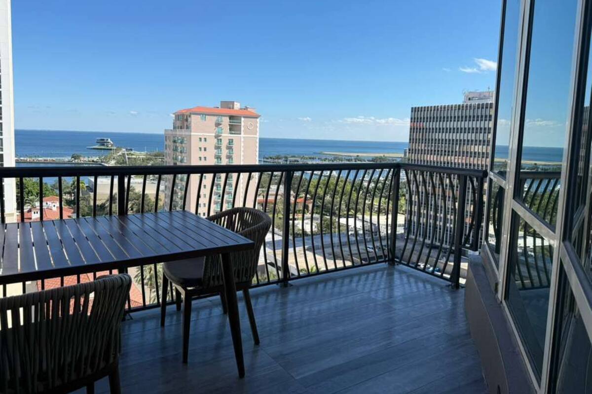 Un balcón con vista al mar, una mesa y sillas.