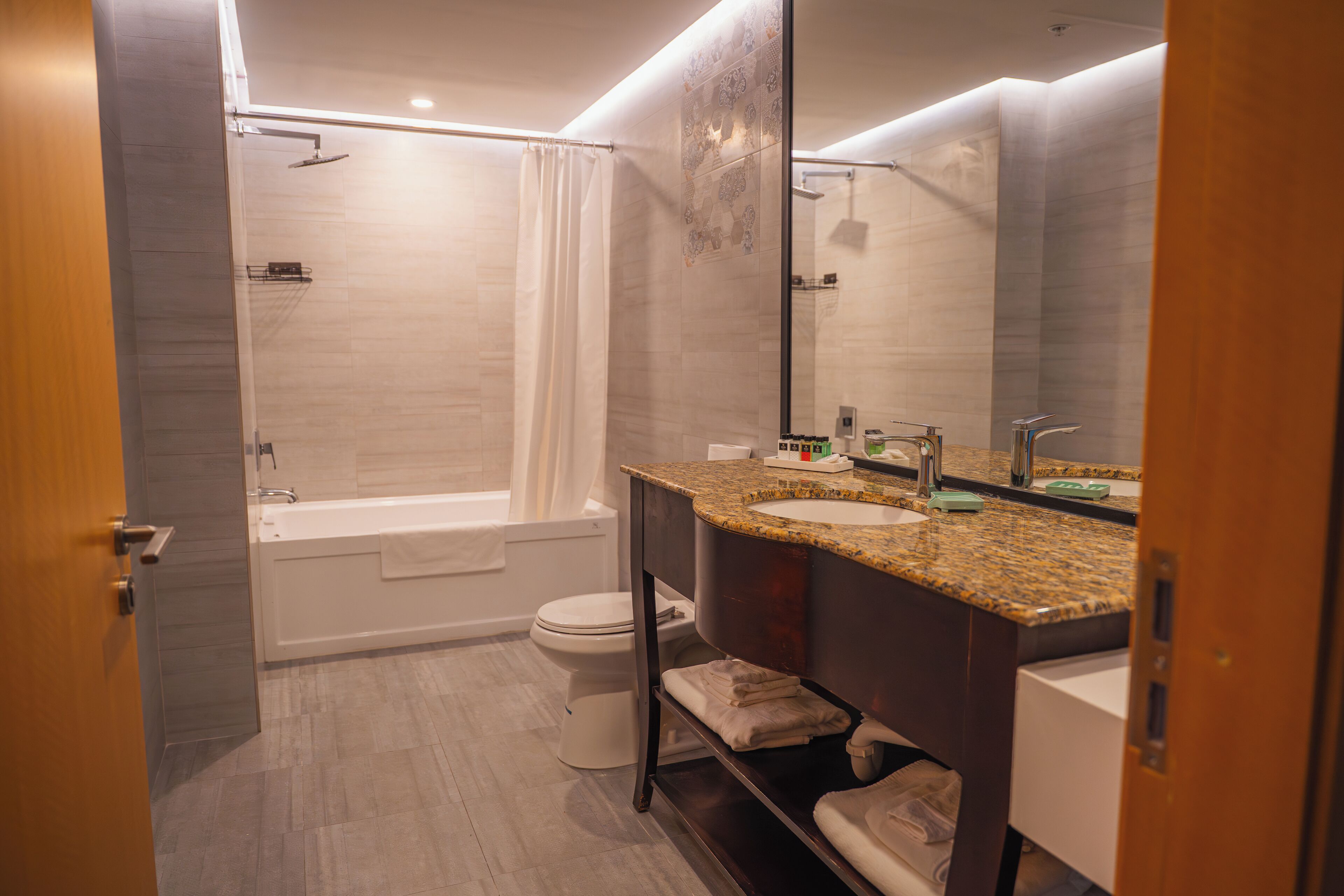 A modern bathroom with a bathtub, toilet, and vanity with a sink and mirror.