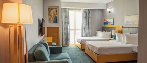 A hotel room with two beds, a sofa, a TV, and a window with curtains.