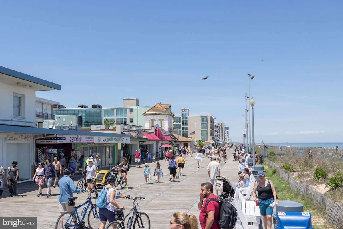 Un paseo marítimo con tiendas y restaurantes, una vía peatonal y vistas a la playa.