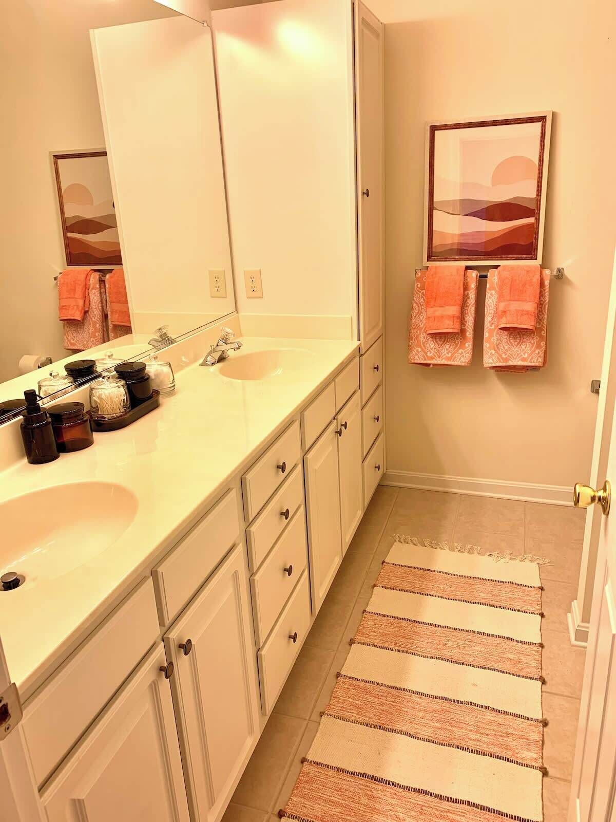 Une salle de bain avec deux lavabos, un grand miroir et un porte-serviettes avec des serviettes.