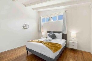 A modern bedroom with a bed, bedside tables, and a window with curtains.