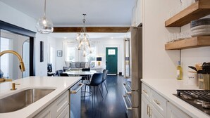 Une cuisine moderne dotée d’un îlot central, d’appareils électroménagers en acier inoxydable et de poutres en bois.