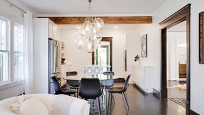 Une cuisine moderne avec un coin repas, des poutres apparentes en bois au plafond et un lustre.