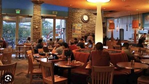 An indoor dining area with multiple tables and chairs, a stone wall, and a large hanging light fixture. - Location! Location! Amazing *Hidden Gem* -NE Heights! Family and pet friendly 🐶  (Albuquerque)