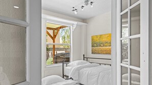 A bedroom with a bed, a window with a view of trees, and a painting on the wall. - Location! Location! Amazing *Hidden Gem* -NE Heights! Family and pet friendly 🐶  (Albuquerque)