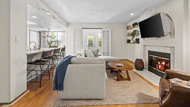 A modern living room with a fireplace, a television mounted on the wall, and a dining area with a bar. - Location! Location! Amazing *Hidden Gem* -NE Heights! Family and pet friendly 🐶  (Albuquerque)