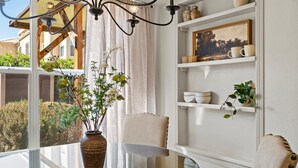 A dining area with a glass table, chairs, a vase with flowers, and a chandelier. - Location! Location! Amazing *Hidden Gem* -NE Heights! Family and pet friendly 🐶  (Albuquerque)