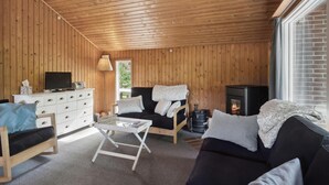 A cozy cabin interior with wooden walls, a sofa, a TV, a fireplace, and a window. - Awesome home in Eskebjerg with WiFi (Eskebjerg)