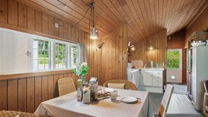 A wooden cabin with a dining area featuring a table set for two, wicker chairs, and a view of the outdoors through large windows. - Awesome home in Eskebjerg with WiFi (Eskebjerg)