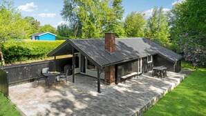 A rustic cabin with a covered patio, a brick chimney, and a small deck. - Awesome home in Eskebjerg with WiFi (Eskebjerg)