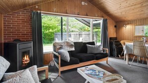 A cozy living room with a fireplace, a sofa, and a dining area with chairs and a table. - Awesome home in Eskebjerg with WiFi (Eskebjerg)