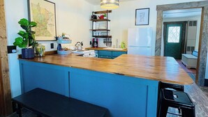 A kitchen with a wooden countertop, a bench, and a hanging light fixture. - Charming 1BR riverside cabin in Brainerd, MN. River sunsets, stocked kitchenette, fire pit, 10 min to downtown. Ideal for couples, small families & remote workers seeking a peaceful Up North escape. (Daggett Brook Township)