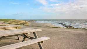 Ein Picknicktisch mit Bänken am Kiesweg direkt am Meer.