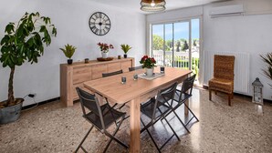 A dining area with a wooden table, chairs, potted plants, and a wall clock. - 2 bedroom amazing apartment in Carpentras (Carpentras)