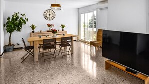 A modern living room with a large flat-screen TV, a wooden dining table with chairs, a potted plant, and a large window. - 2 bedroom amazing apartment in Carpentras (Carpentras)