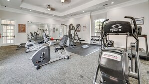 A gym with various exercise equipment, including treadmills and weight machines, in a well-lit room with large windows. - 10 Mi to Disney! Family-Friendly Resort Getaway (Davenport)
