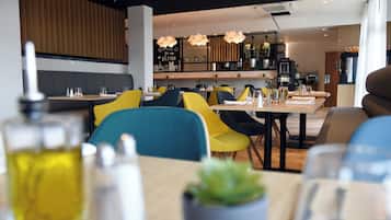 Un restaurante moderno con sillas amarillas y azules, paneles de madera e iluminación colgante.