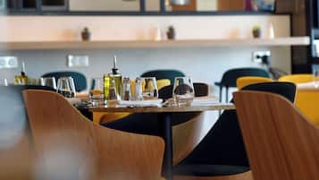 A modern dining area with wooden chairs, a table set with glasses and cutlery, and pendant lighting.