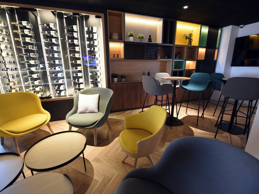A modern interior with a wine rack, seating area, and a TV screen.