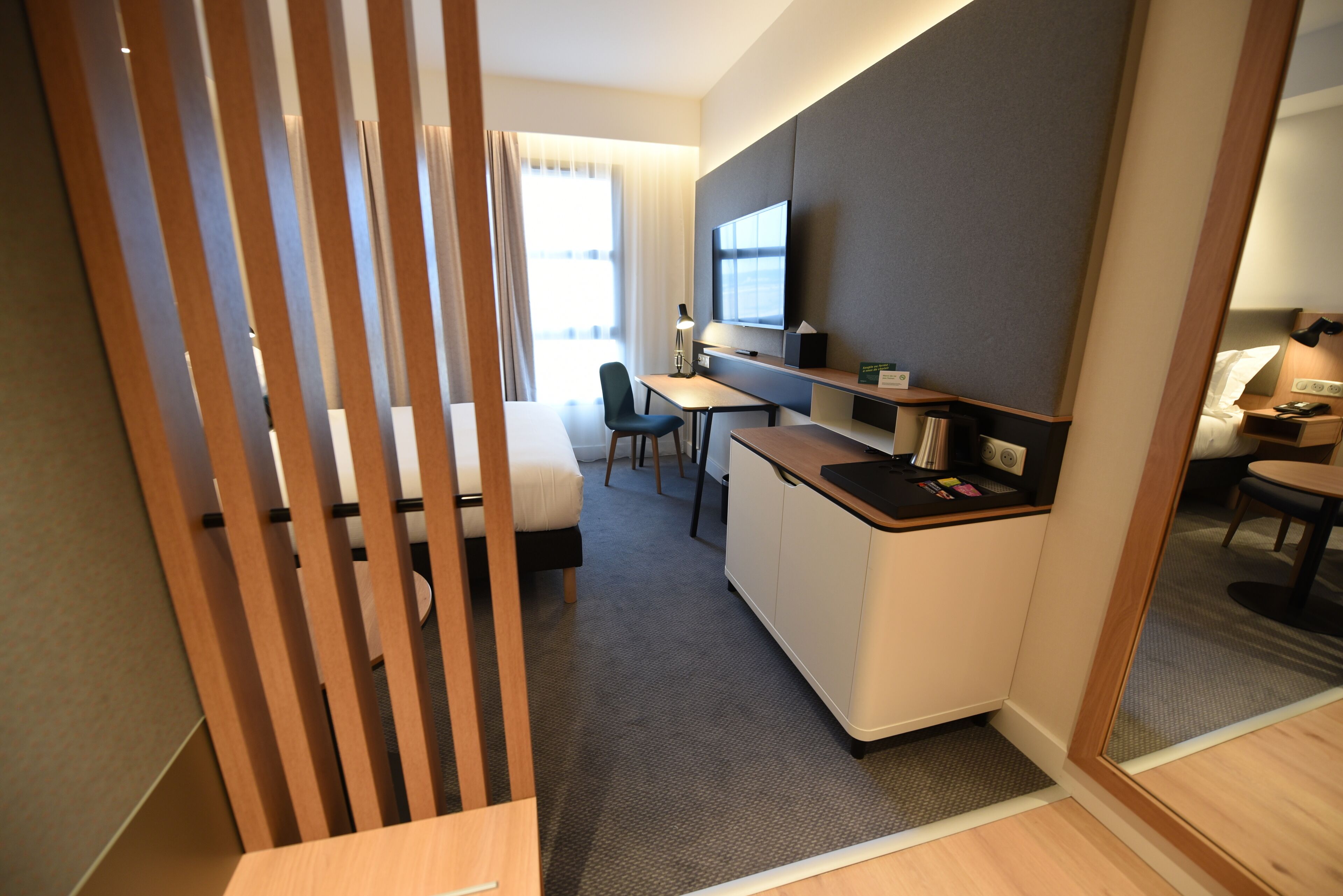 Une chambre d’hôtel compacte comprenant un coin cuisine, un bureau, une chaise et un lit.