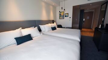 Et moderne hotelværelse med to store senge, et skrivebord og en stol.