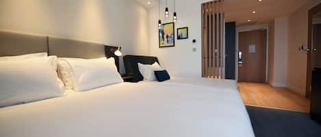 A modern hotel room with a large bed, a bedside table, and a wall-mounted light fixture.