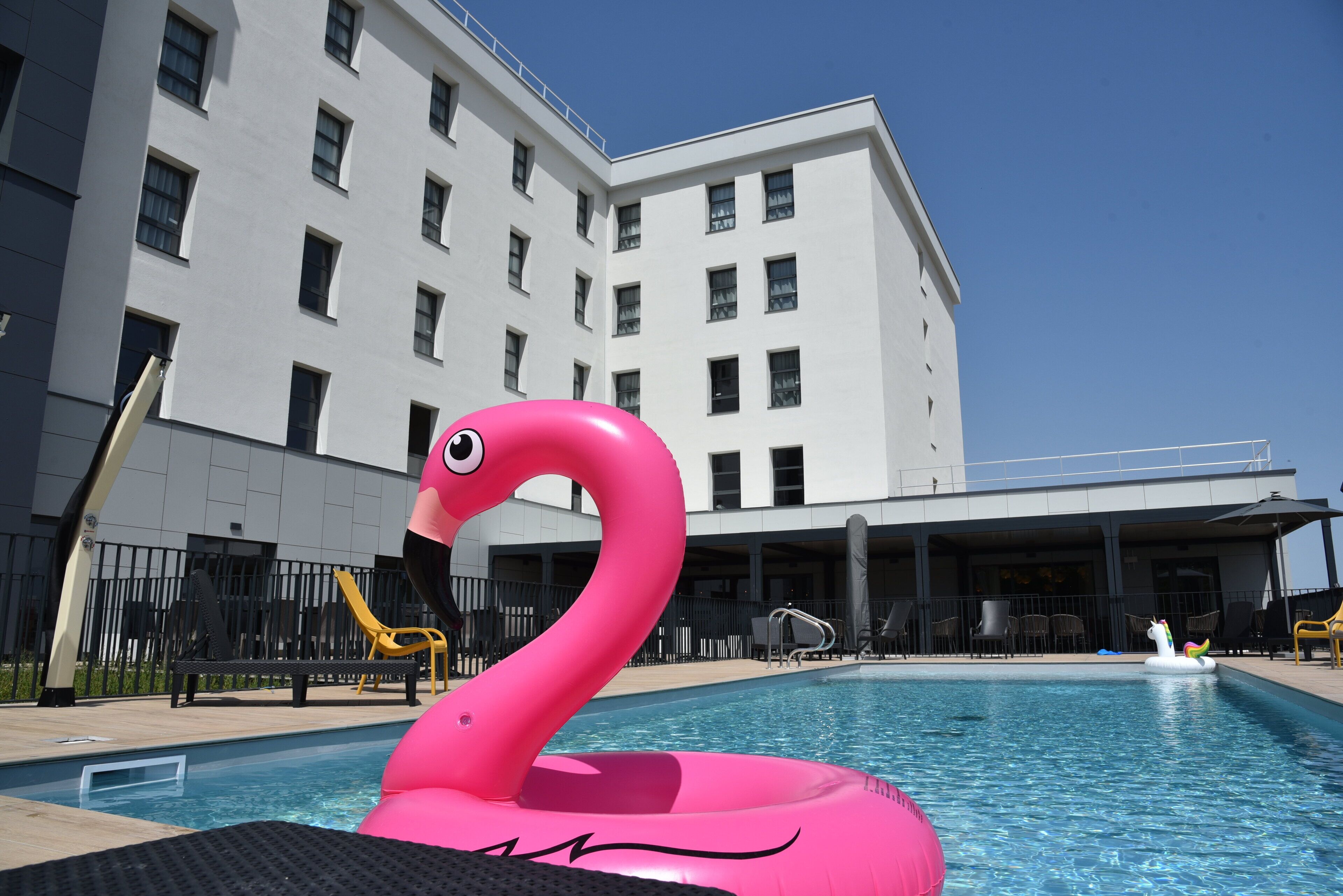 A swimming pool with a pink flamingo float and a unicorn float.