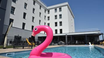 A swimming pool with a pink flamingo float and a unicorn float.