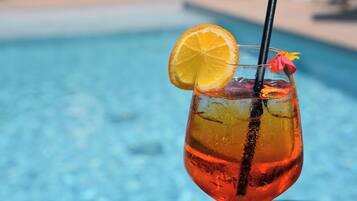 Ein Cocktail mit Orangenscheibe und Blütenblumen-Garnitur, platziert in Poolnähe.