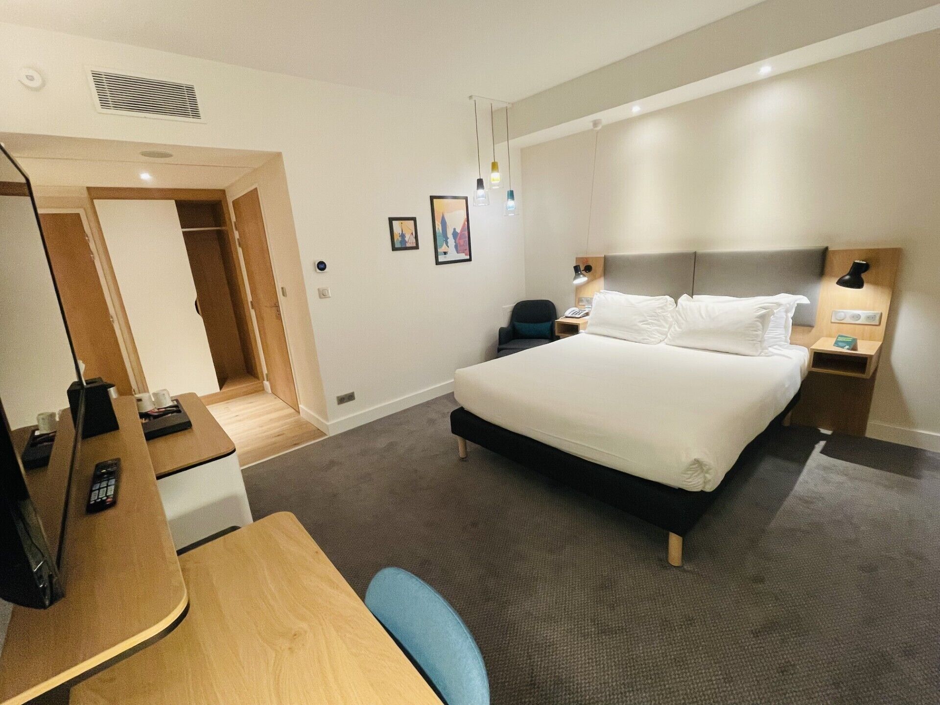 Une chambre d’hôtel avec un grand lit, des tables de chevet, un bureau avec une chaise et une armoire.