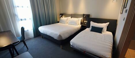 Habitación de hotel con dos camas, un escritorio y una silla.
