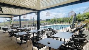 An outdoor patio with tables and chairs, a pool, and a view of the landscape. - Holiday Inn Dijon Sud Longvic by IHG (Longvic)