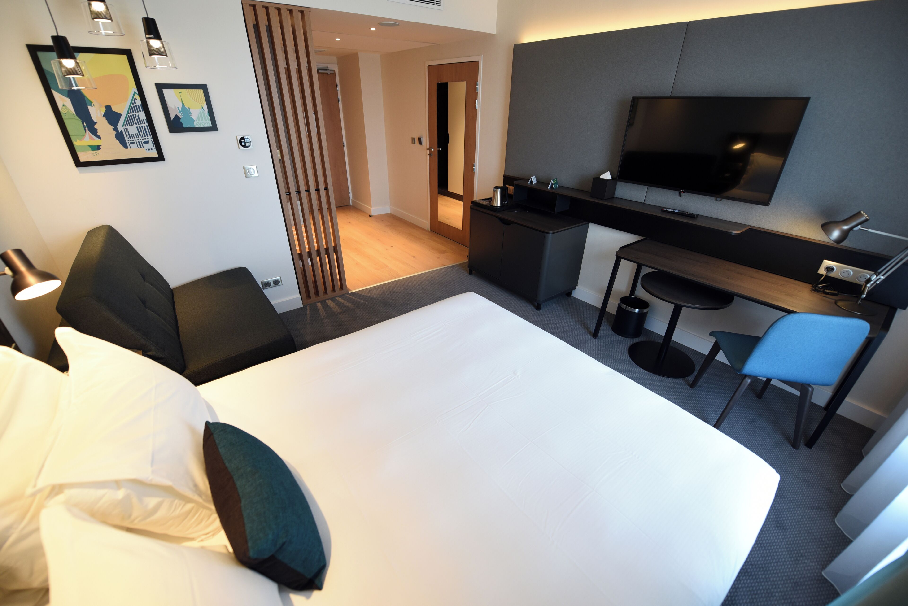 A hotel room with a large bed, a desk with a computer, a TV, and a chair.