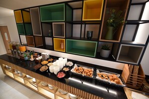 Un bufé con diversos alimentos y diferentes dispensadores de bebidas.