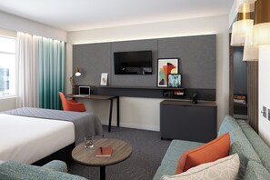 Habitación de hotel con dos camas, un escritorio, un televisor y un sofá.