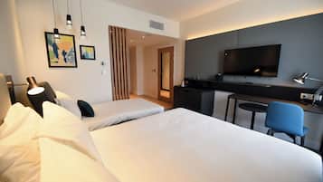 Ein Hotelzimmer mit zwei Betten, einem Schreibtisch, einem Fernseher und einem Sessel.