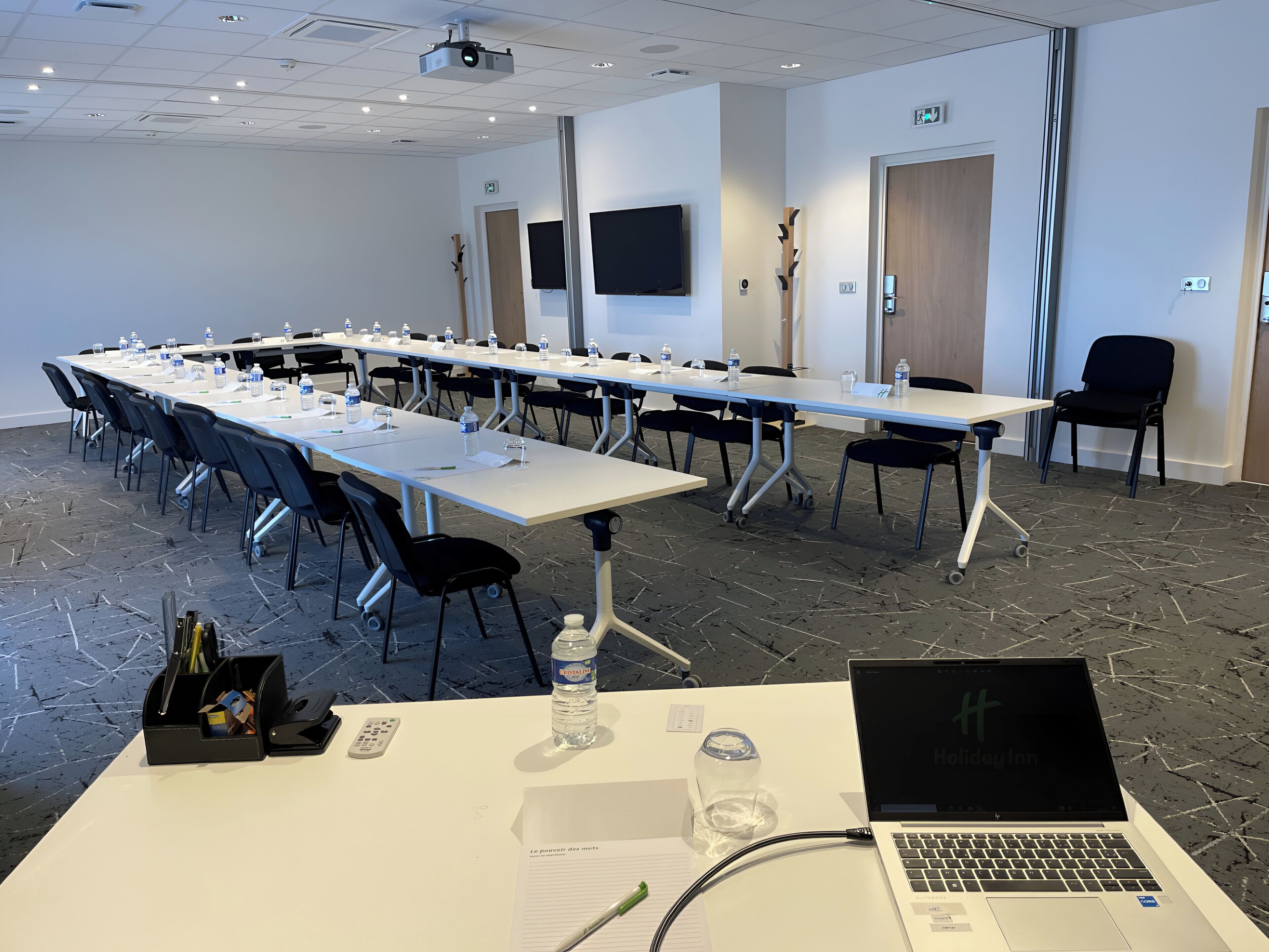 A conference room with a long table, chairs, a projector, and a laptop.
