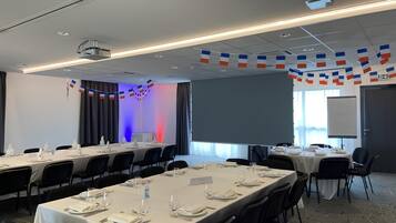A conference room with long tables set for a meeting, a projector, and a screen.
