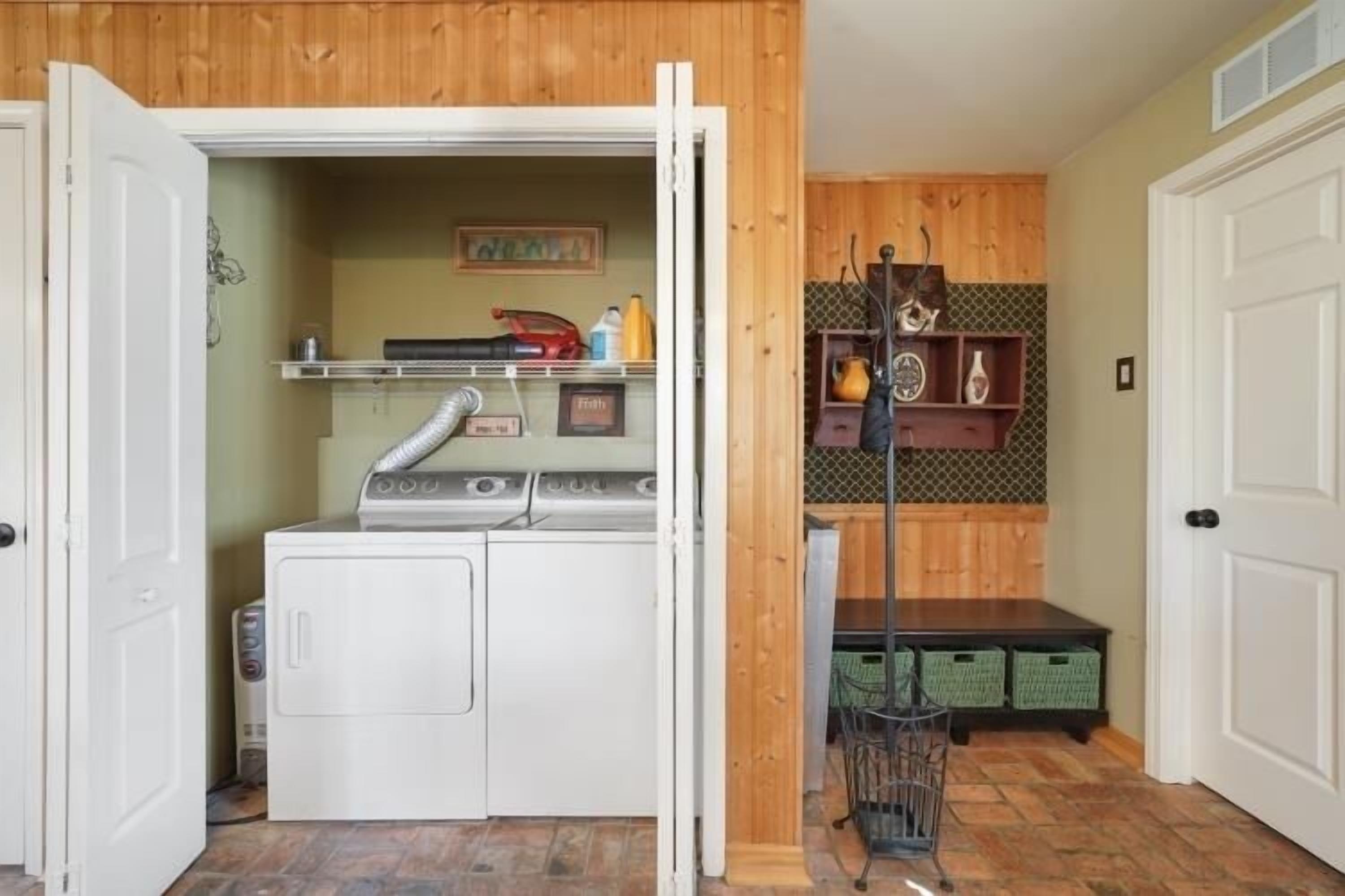 A laundry room with a washer and dryer, shelves with toiletries, and a metal rack.