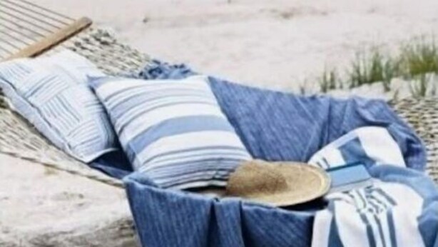 Une chaise de plage avec un coussin à rayures et une serviette bleue.