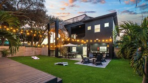 Ein modernes Haus mit Terrasse, Sitzgelegenheiten im Freien und Lichterketten.