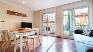 A dining area with a table and chairs, a television, and a sliding glass door leading to a balcony. - Apartament Sant Mateu (Vilassar de Mar)