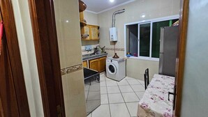 A compact kitchen with a washing machine, a window, and a refrigerator. - Appartement (Tangier)