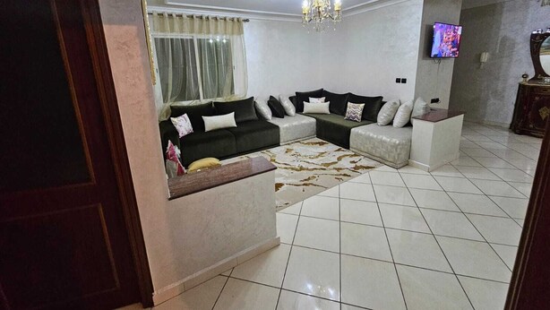 A living room with a sofa set, a chandelier, a television, and a tiled floor. - Appartement (Tangier)