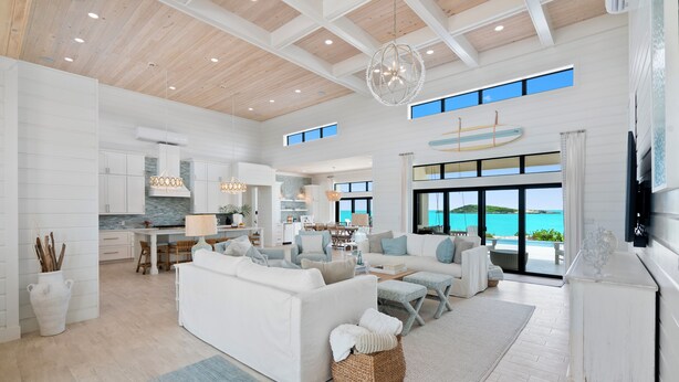 A spacious living area with a large white sofa, a dining table, and a kitchen in the background. - CIESTA SANDS- Beachfront Luxury, Top Beach, 4 bedrooms w private bath, Pool (Moore Hill)