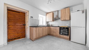 Een moderne keuken met houten kastjes, een inbouwoven en een witte koelkast.