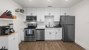 A modern kitchen with white cabinets, stainless steel appliances, and wooden flooring. - Barrel Retreat in the Heart of Downtown Phoenix (Phoenix)