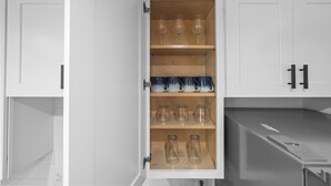 A kitchen with white cabinets, a wooden shelf with wine glasses and mugs, and a countertop with a knife block. - Barrel Retreat in the Heart of Downtown Phoenix (Phoenix)