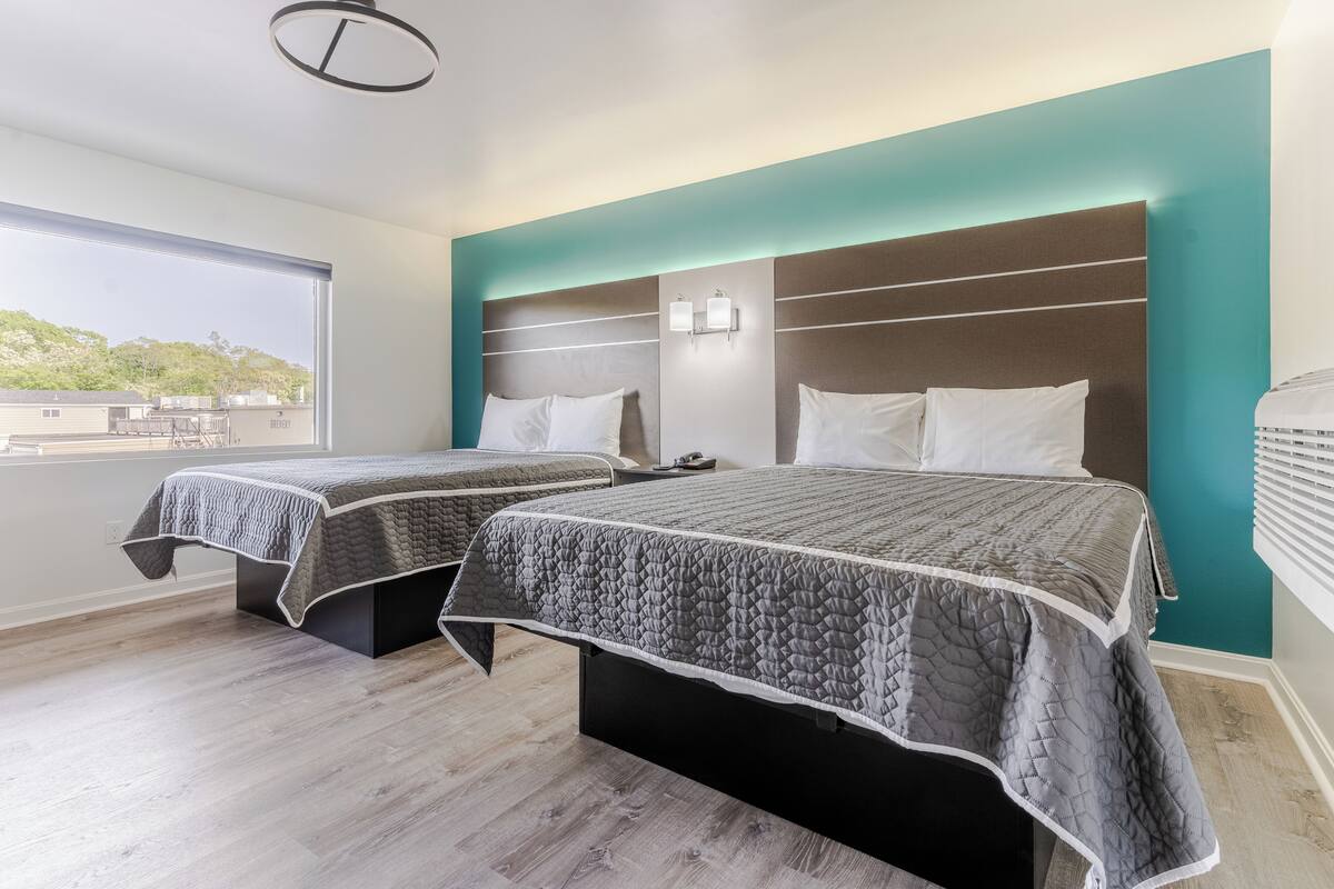 A hotel room with two beds, a view of the city, and a modern design.